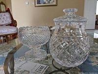 Photo showing both Waterford Crystal pieces, footed bowl on left and lidded jar on right on glass table.