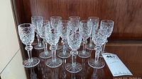 Twelve crystal cordial glasses on a mirrored shelf, angled view