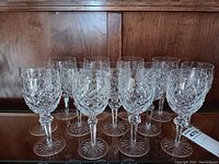 Thirteen glasses arranged on wooden shelf, angled view