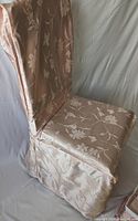 Front and side view of one light pink damask chair cover showing fabric texture and drape on a chair.