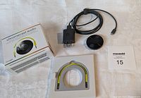 Photo showing Google Chromecast Audio device, original box, power adapter with cable, user guide insert, and MaxSold bid card.