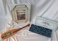 Lot view showing two nautical-themed picture frames, a wooden decorative miniature canoe paddle with a photo insert, and a blue ceramic serving dish with anchors and its original box.