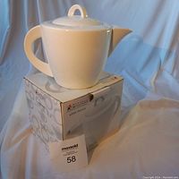 White ceramic teapot sitting on top of its original box with Maxwell Williams branding.