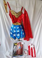 Photo of the full costume components displayed: red top with gold emblem, blue star skirt, gold belt, red cape, gold arm cuff, and leg covers