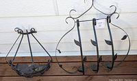 Pair of wrought iron-style garden wall planters on a wooden deck with white wall background