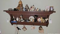 Wide view of shelf with multiple cat figurines of various materials and styles