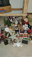 Overview image showing the full assortment of snowman ornaments and Christmas decorations on carpeted floor under wooden furniture structure.