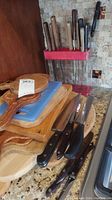 Stack of wood and plastic cutting boards with knives laid out in front