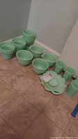 Full set of jadeite green glass items including bowls, cups, and a tray arranged on floor