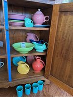 Full cabinet shot with plates, teapot, saucer, small gravy boat, serving bowl, pitchers and tumblers
