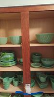 Wooden cabinet shelf with jadeite bowls and plates stacked
