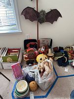 Overview of assorted Halloween, Thanksgiving, and Easter decorations including bat wall hanging, paper plates, ceramic pumpkin, and bags with decor items.