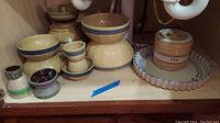 Full set of 16 pottery pieces on wooden shelf including bowls, canister, tray and small decorative pieces.