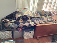 Black and neutral chain-stitched diamond quilt draped on bench