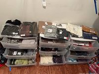 Full view of sorted plastic drawers containing various packaged women's clothing items in neutral and dark tones.
