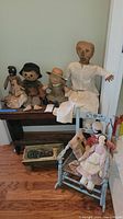 Bench, dolls, rocking chair and stool arranged against wall