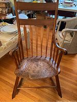 Front view of the antique wooden arrow back rocking chair, showing wear on seat and overall structure.