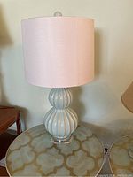 Front view of the blue ceramic lamp with pink lampshade on glass table