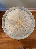 Overhead photo of the round wood table top with hand-painted radial pattern and gold leafing.