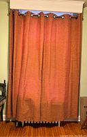 Curtain panels hanging on a white curtain rod over a radiator and window, showing full length and color.