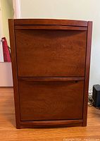 Front view of the two-drawer filing cabinet showing the cherry wood stain and drawer fronts.