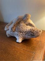 Side angle showing the hunter figure reclining on the seal, highlighting the texture and porous nature of the whale bone.