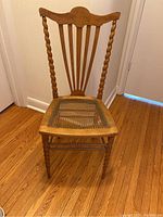 Front view of wooden chair showing barley twist legs and spindles with woven cane seat