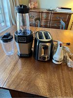 KitchenAid hand mixer with beaters, Black & Decker toaster, and Ninja Professional blender on wooden table.