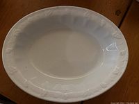 Photo of a white oval ironstone serving dish with embossed grape and leaf pattern and smooth glossy finish.