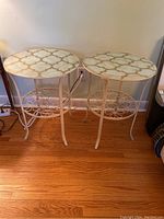 Two round metal IKEA tables with glass tops on hardwood floor. Light cream paint base with bottom circular floral wire rack. Tables are next to a beige wall.