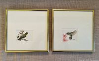 Pair of framed watercolour paintings side-by-side showing Ruby Crowned Kinglet and Ruby Throated Hummingbird in gold-tone frames on a fabric background.