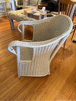 Side view of vintage painted wicker arm chair, showing painted white woven wicker construction and rounded armrest design.