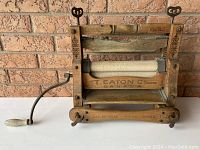 Front view of wooden antique laundry wringer showing hand crank and rollers with brand text.