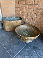 Both copper planters shown side by side against brick background on tile floor.
