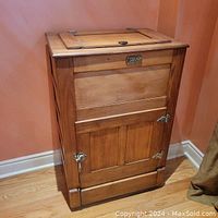 Full front view of antique solid oak ice chest showing wood grain, door with metal latches, and overall shape.