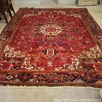 Full view of red Persian rug laid flat on carpeted floor
