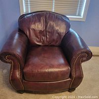 Front view of brown leather armchair with nailhead trim and rolled arms.