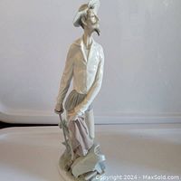 Side view of the porcelain figurine showing Don Quixote holding a sword, wearing a hat and standing on a base with a broken piece.