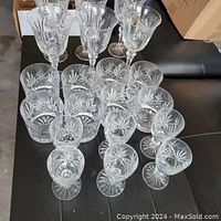 Full view of the 20-piece set of pinwheel cut crystal glassware including wine glasses, sherry glasses, and rocks glasses displayed on a black surface.