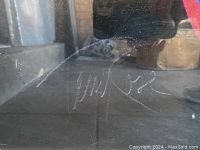 Close-up of the artist signature on the print, handwritten in white ink near the bottom right.