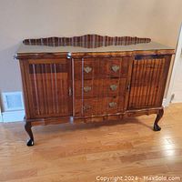Full front view of antique Imbuia wood sideboard showing ball and claw feet, three centrally located drawers and fluted cabinet doors on each side.