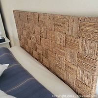Full side view of queen-sized woven block seagrass headboard attached to bed frame