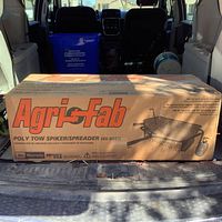 Photo of unopened Agri-Fab Poly Tow Spiker/Spreader box in vehicle trunk showing brand and product model 45-0543.
