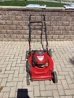 Red Craftsman lawnmower viewed from the front showing handle bars, wheels, and engine cover with branding.