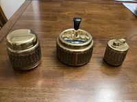 Front view of all three items arranged on wooden table showing brass and metal patterned bodies