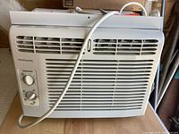 Frigidaire air conditioner front view showing controls, grille and power cord.