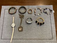 Full lot shown together on grey fabric background including bracelets, necklace, and watches