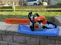 Left side view of Stihl MS 170 chainsaw mounted on blue surface, showing bar, scabbard and body