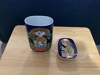 Vase and candy dish placed on wooden table showing colorful detailed designs and shapes.