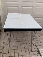 Top view of the kitchen table showing the white textured surface with the table leaf closed, highlighting the split in the middle.